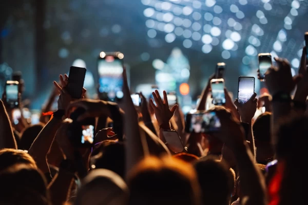 Persone in un concerto che filmano con i loro smartphone.